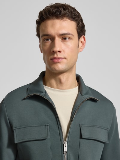 Mężczyzna nosi Regular Fit Sweatjacke aus Baumwoll-Mix von Marc O'Polo, bawełniany scuba materiał, kolor jednolity, dwie kieszenie na piersi, długi rękaw, stójka, zamek dwukierunkowy, label patch; zbliżenie na górną część ciała, widok z przodu.