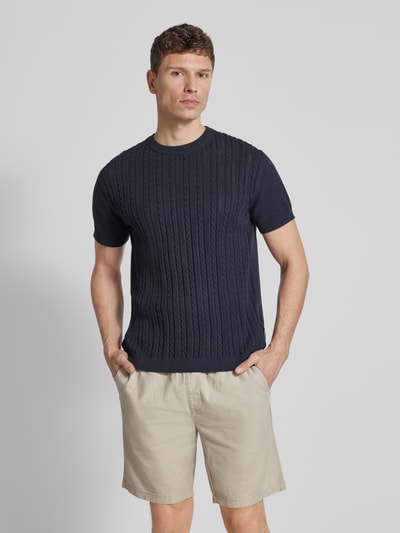 Męski model nosi T-Shirt mit Zopfmuster od Lindbergh, bawełna, prosty krój, imitacja dzianiny, okrągły dekolt, ścieg warkoczowy, długość tyłu w rozmiarze M 68 cm, granatowy, pełny widok z przodu.