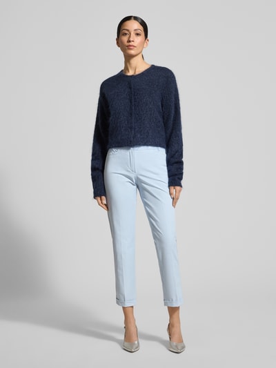 Frauenmodel trägt Chino aus Techno Cotton Superstretch Modell 'UTE' von Raffaello Rossi in Hellblau mit Straight Fit, Eingriff- und Gesäßtaschen, elastischer Material-Mix, Bügelfalten, verkürzte Passform, Knopf- und Reißverschluss, fixierte Beinumschläge und Gürtelschlaufen, Ganzkörperansicht von vorne.