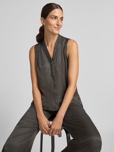 Frauenmodel trägt Regular Fit Blusentop aus reiner Viskose Modell 'Zenaya' von someday, satinierte dunkelgraue Oberfläche, Nahaufnahme Oberkörper.