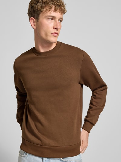 Männermodel trägt Regular Fit Sweatshirt mit Baumwoll-Anteil Modell 'Bradley' von JACK & JONES in Braun, Struktur glatt, Nahaufnahme Oberkörper. Herren Sweatshirt, Rundhalsausschnitt, Langarm, gerippte Blende und Abschlüsse, Logo-Label, Rückenlänge 66 cm, Ärmellänge 64 cm.