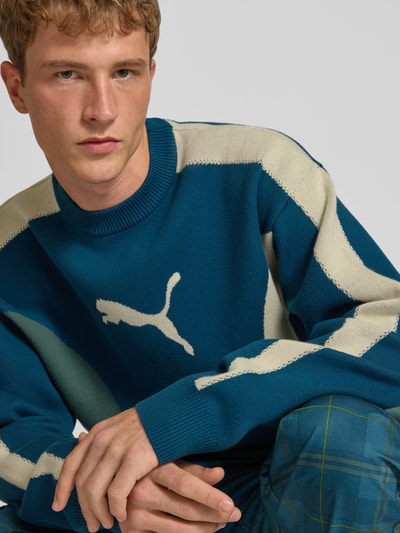 Mężczyzna nosi Relaxed Fit Pullover aus Baumwoll-Mix od PUMA, niebieski sweter z mieszanki bawełny z białymi wstawkami, Nahaufnahme Oberkörper, Herren Pullover von PUMA Performance