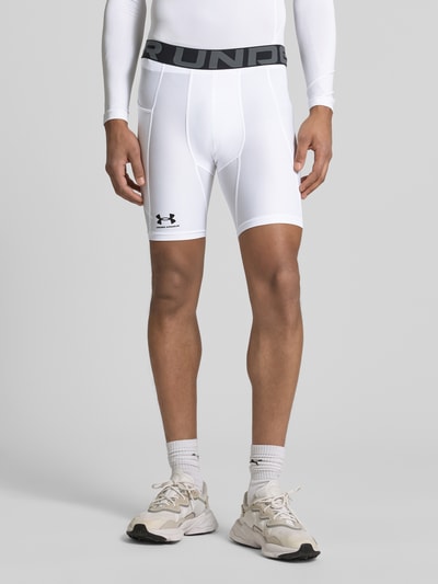 Männermodel trägt Shorts mit elastischem Logo-Bund von Under Armour in Weiß, Material-Mix mit Stretch-Anteil, Label-Print, körpernaher Schnitt, Bundweite 37 cm, Innenbeinlänge 21 cm, Ganzkörperansicht von vorne.