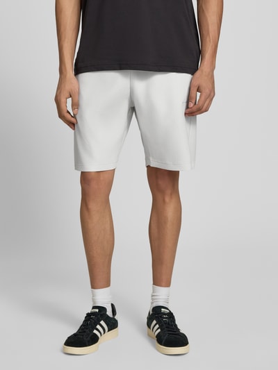 Männermodel trägt Herren Shorts mit Logo Modell 'Troy' von Pegador im weißen Material-Mix mit Stretch-Anteil, Regular-Fit, Ganzkörperansicht von vorne.