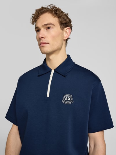 Männermodel trägt Loose Fit Poloshirt mit Label-Stitching von ARMANI EXCHANGE, dunkelblauer Baumwoll-Mix mit Stretch-Anteil, Nahaufnahme Oberkörper.