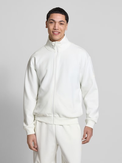 Männermodel trägt Regular Fit Sweatjacke aus reiner Baumwolle von adidas Sportswear, unifarben, Stehkragen, Logo-Print, Ganzkörperansicht von vorne.