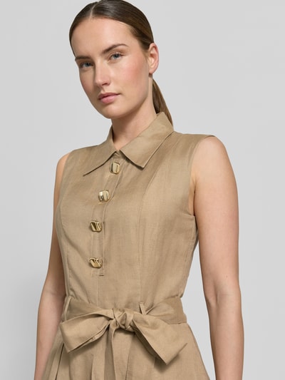 Kobiece model nosi tailliertes Freizeitkleid aus Leinen-Viskose-Mix Modell 'KALEISI' od HUGO, efekt: jednolity kolor, tkanina cieniowana, ozdobne guziki, wiązany pasek, szlufki, wysokie zapięcie, długość midi, szerokie ramiączka, wpuszczane kieszenie, wykończenie: mieszanka lnu i wiskozy. Zbliżenie na górę sylwetki.