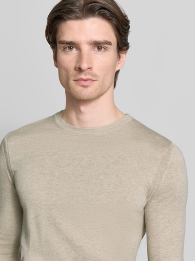 Mężczyzna nosi Strickpullover mit gerippten Abschlüssen Modell 'WALLIE' von CINQUE, bawełniano-lyocellowy krój slim fit, beżowa faktura, okrągły dekolt, zbliżenie na górną część ciała.