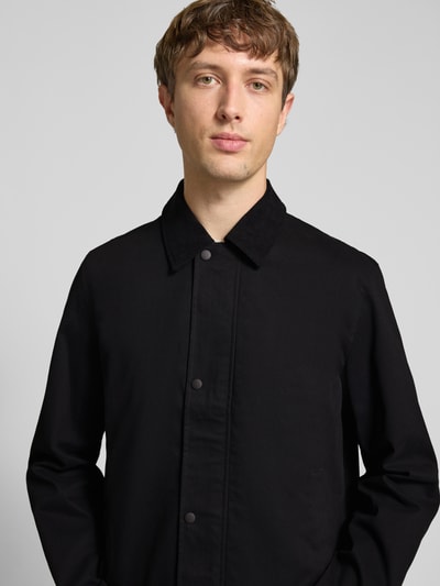 Männermodel trägt Jacke mit Umlegekragen Modell 'GRAHAM' von Jack & Jones in Schwarz, Regular Fit, Knopfleiste, Nahaufnahme Oberkörper.