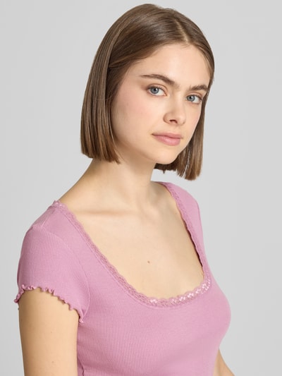 Frauenmodel trägt Slim Fit T-Shirt aus Viskose-Mix mit Spitzenbesatz von Review in Rosa, feine Rippstruktur, Nahaufnahme Oberkörper. Damen T-Shirt, elastischer Viskose-Mix, Rundhalsausschnitt, Rückenlänge bei Größe S: 51 cm.