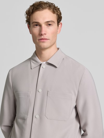Männermodel trägt Regular Fit Overshirt mit Brusttaschen von MCNEAL in hellem Grau, Material-Mix mit Stretch-Anteil, Nahaufnahme Oberkörper.