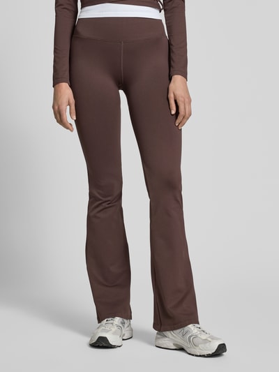 Frauenmodel trägt Flared Fit Leggins mit breitem Bund von aim'n in Braun, elastischer Material-Mix, Ganzkörperansicht von vorne.