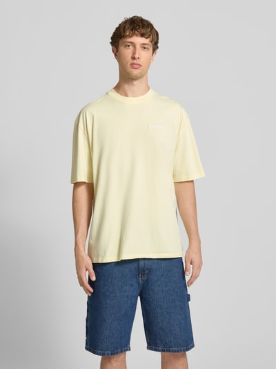 Männermodel trägt Oversized T-Shirt mit Label-Stitching von Pegador, hellgelb, Baumwoll-Mix, Rundhalsausschnitt, Ganzkörperansicht von vorne. Herren T-Shirt, Rückenlänge bei Größe M: 70 cm.