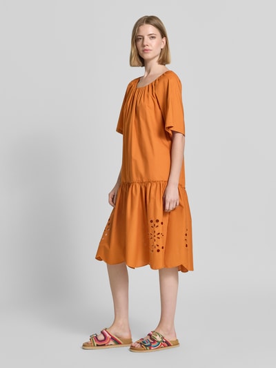 Frauenmodel trägt Knielanges Kleid mit Lochstickerei und Rundhalsausschnitt von Christian Berg Woman in Orange, Reine Baumwolle, Straight Fit, Knielänge, Rundhalsausschnitt mit Raffungen, Lochstickerei, Rückenlänge bei Größe 36: 106 cm, Brustweite bei Größe 36: 48 cm, Ärmellänge bei Größe 36: 23 cm, fließender Stoff, ganzkörperansicht von vorne.