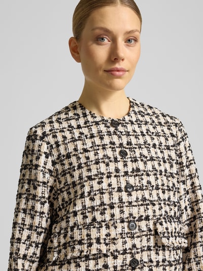 Frauenmodel trägt Regular Fit Blazer in Bouclé-Optik Modell 'Jenifer' von JOOP! in Creme und Schwarz, Nahaufnahme Oberkörper. Rückenlänge 52 cm, Brustweite 49 cm, Ärmellänge 91 cm, aufgesetzte Taschen, durchgängige Knopfleiste, Rundhalsausschnitt, Größe 36.
