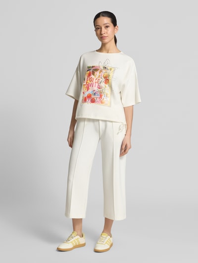 Vrouwenmodel draagt Relaxed Fit T-Shirt mit Logo-Print van Christian Berg Woman, elastische materiaalmix met modal, ronde hals, wit met kleurrijke print, volledige lichaamsvoorzijde.