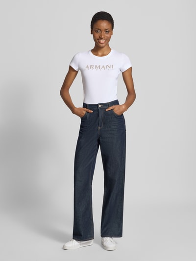 Vrouwenmodel draagt Slim Fit T-Shirt met labelprint van Armani Exchange, wit met labelprint, mix van katoen en elastaan, ronde hals, ruglengte bij maat S 54 cm, Ganzkörperansicht von vorne.