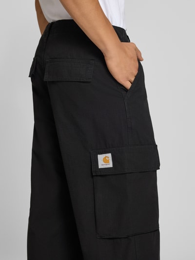 Männermodel trägt schwarze Cargohose aus Baumwolle Modell 'Columbia' von Carhartt Work In Progress mit Cargotaschen, Nahaufnahme Oberschenkel