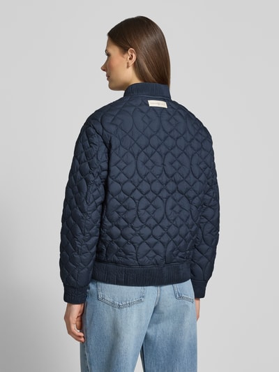 Männermodel trägt Jacke mit Stehkragen und Eingrifftaschen von Fuchs Schmitt, krój regular fit, ciemnoniebieski, przeszycia, widoczne kieszenie, długość tyłu w rozmiarze 36: 58 cm, szerokość ramion w rozmiarze 36: 48 cm, szerokość klatki piersiowej w rozmiarze 36: 57 cm, długość rękawa w rozmiarze 36: 56 cm, tekstura pikowana, widoczne mankiety, jeansy, całopostaciowe ujęcie z tyłu