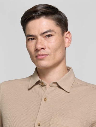 Männermodel trägt Regular Fit Freizeithemd aus Baumwoll-Mix von s.Oliver RED LABEL in Beige mit Waffelstruktur, Kentkragen, Nahaufnahme Oberkörper.