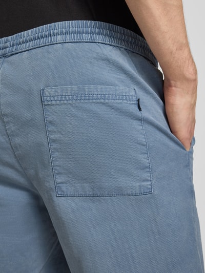 Männermodel trägt Shorts mit elastischem Bund Modell 'JAIDEN CARTER' von Jack & Jones aus Baumwoll-Elasthan-Mix in Blau, Strukturmuster, Nahaufnahme Rückansicht, Regular-Fit, Kontext: Herren Shorts, Bundweite Größe M 43 cm, Innenbeinlänge 20 cm.