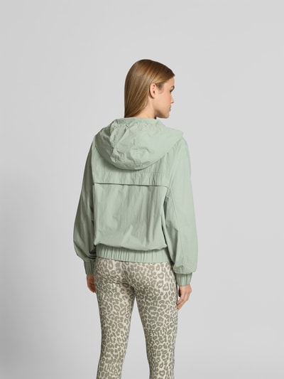 Frauenmodel trägt Regular Fit Jacke mit Logo-Stitching von Lala Berlin in Hellgrün mit Kapuze, Tunnelzug, Eingrifftaschen, Reißverschluss, Rückenlänge bei Größe S 53 cm, Brustweite 60 cm, Ärmellänge 59 cm, Ganzkörperansicht Rückansicht.