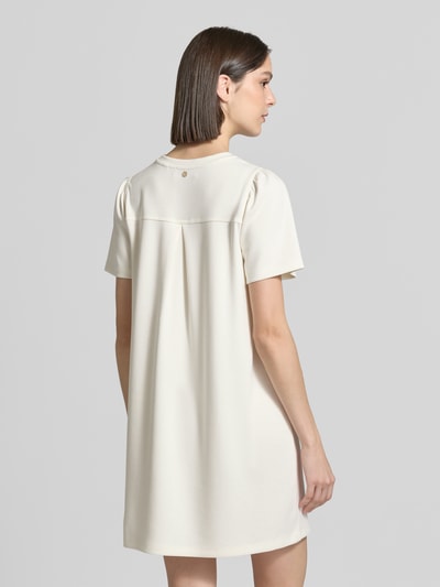 Frauenmodel trägt T-Shirt-Kleid aus Modal-Mix mit Rundhalsausschnitt von Rich & Royal in Creme, Gerader-Schnitt, Minikleid, Rückenlänge 83 cm, Brustweite 40 cm, Ärmellänge 24 cm, Struktur glatt, Ganzkörperansicht Rückansicht.