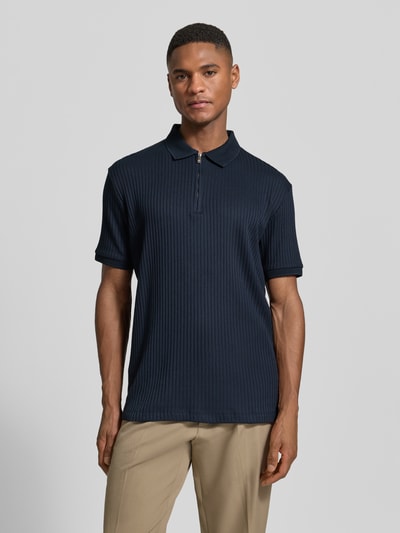 Männermodel trägt Regular Fit Poloshirt mit Baumwoll-Anteil Modell 'FAVE' von SELECTED HOMME in Dunkelblau, Rippenstruktur, Ganzkörperansicht von vorne.