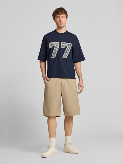 Männermodel trägt T-Shirt mit Ketten-Stickerei und Rundhalsausschnitt von REVIEW, Relaxed-Fit, Reine Baumwolle, Ganzkörperansicht von vorne.