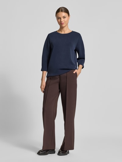 Modelka nosi Comfort Fit Sweatshirt aus Modal-Mix od s.Oliver RED LABEL, gładki granatowy materiał scuba, 3/4 rękaw, okrągły dekolt, boczne rozcięcia, widok całej sylwetki z przodu.