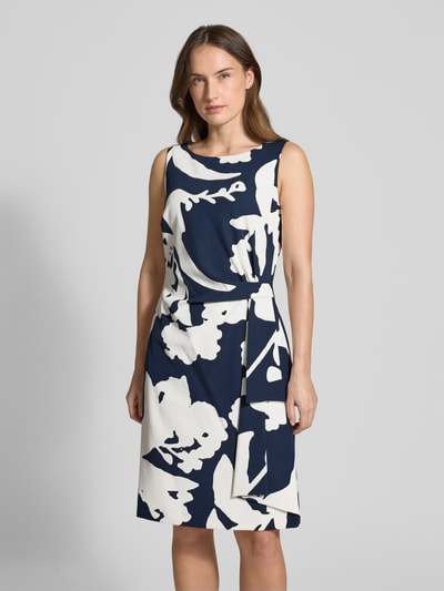 Frauenmodel trägt Knielanges Cocktailkleid in Wickel-Optik von Vera Mont, elastischer Material-Mix, dunkelblau-weiß, Ganzkörperansicht von vorne
