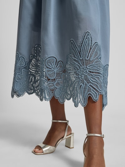 Frauenmodel trägt Midirock aus Lyocell-Mix Modell 'Molly' von Copenhagen Muse mit floralen Loch-Stickereien, Kellerfalte, Nahaufnahme Unterteil. Damen Midirock, A-Linie, Bundweite 37 cm, Gesamtlänge 87 cm, Größe S, blauer Stoff, strukturierte Textur.