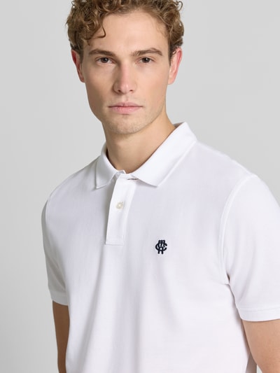 Męski model nosi Regular Fit Poloshirt mit Label-Stitching von MCNEAL z bawełny, krój regular fit, listwa guzikowa, długość tyłu 70 cm w rozmiarze M, zbliżenie na górną część ciała