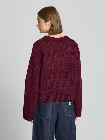 Frauenmodel trägt Relaxed Fit Pullover im Chunky Knit Look Modell 'DORTHEA' von PIECES, bordeaux, grobe Strickstruktur, Ganzkörperansicht Rückansicht.
