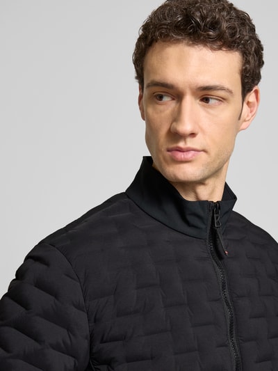Männermodel trägt Jacke mit Zweiwege-Reißverschluss Modell 'GRAY3' von FIRE + ICE in Schwarz, Material-Mix mit Stehkragen, Nahaufnahme Oberkörper.