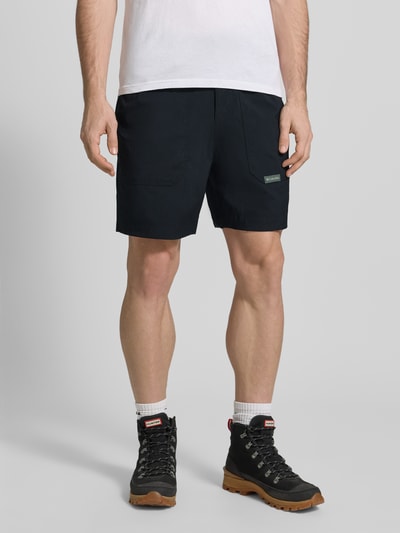 Männermodel trägt Regular Fit Shorts mit Logo-Patch Modell 'Landroamer' von COLUMBIA aus Elastischer-Material-Mix in Schwarz mit AufgesetzteTaschen, Elastischer Bund, Knopf-Reißverschluss, Bundweite 38 cm, Innenbeinlänge 18 cm, Ganzkörperansicht von vorne.
