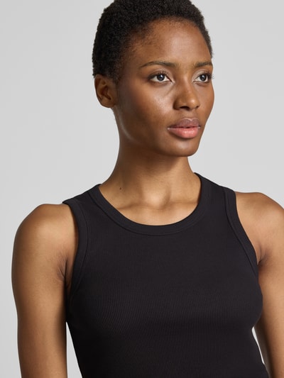 Vrouwenmodel draagt slim fit tanktop uit katoenmix model 'Ilesso' van OPUS in zwart, structuur ribbel, nahaufnahme bovenlichaam.