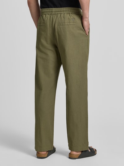 Mannelijk model draagt Regular Fit broek met steekzakken van Wood Wood in mix van linnen en katoen, elastische band, binnenbeenlengte maat M 77 cm, bandwijdte maat M 42 cm, kleur olijfgroen, textuur glad, productcontext heren broek, ganzkörperansicht achteraan.