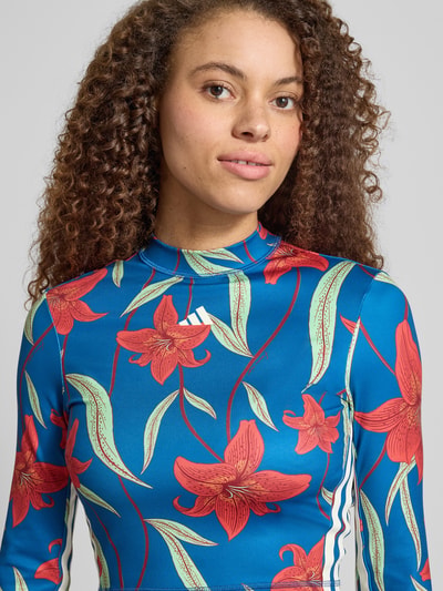 Frauenmodel trägt Slim Fit Sport-Langarmshirt mit Allover-Muster von adidas Sportswear in Blumen-Optik, Kontraststreifen, hochgeschlossen, AEROREADY, Interlock, Nahaufnahme Oberkörper.