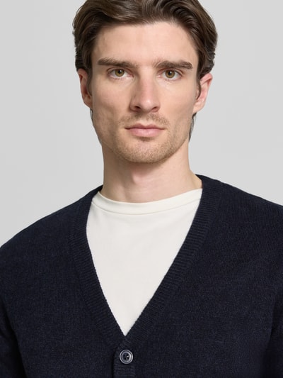 Männermodel trägt Strickjacke mit Knopfleiste Modell 'HEINE' von Casual Friday, Baumwoll-Mix, V-Ausschnitt, Nahaufnahme Oberkörper.