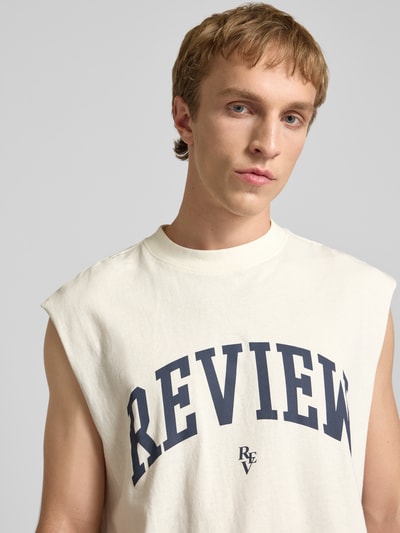 Männermodel trägt Tanktop mit Logo-Print von REVIEW in Offwhite mit schwarzem Schriftzug, reine Baumwolle, Nahaufnahme Oberkörper.