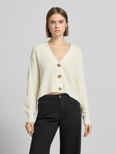 Vrouwenmodel draagt Regular Fit Strickjacke met eenrijige knoopsluiting model 'CAROL NICE' van ONLY, effen, gebreid, cropped, diepe V-hals, lange mouwen, geribde boorden, label stitching, materiaalverwerking: breiwerk. Vooraanzicht bovenlichaam.