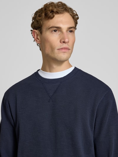 Männermodel trägt Regular Fit Sweatshirt aus katoenmix van Scotch & Soda in donkerblauw met fijne textuur, ronde hals, Nahaufnahme Oberkörper. Heren sweatshirt, katoenmix, regular fit, ronde hals, elastische boordjes, ruglengte maat M 61 cm, mouwlengte 70 cm.