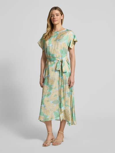 Frauenmodel trägt Midikleid aus Reine Viskose mit Bindegürtel von Rich & Royal, taillierter Schnitt, U-Boot-Ausschnitt, Blumenmuster, Ganzkörperansicht von vorne. Rückenlänge bei Größe 36: 123 cm, Brustweite: 50 cm, Ärmellänge: 9 cm.