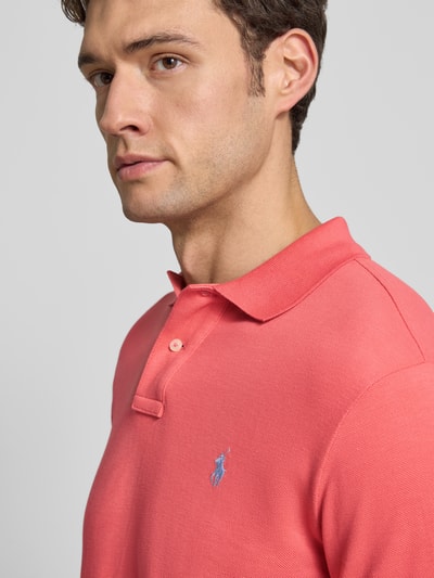 Männermodel trägt Poloshirt mit Label-Stitching von Polo Ralph Lauren in Koralle, Reine Baumwolle, Regular-Fit, Nahaufnahme Oberkörper.