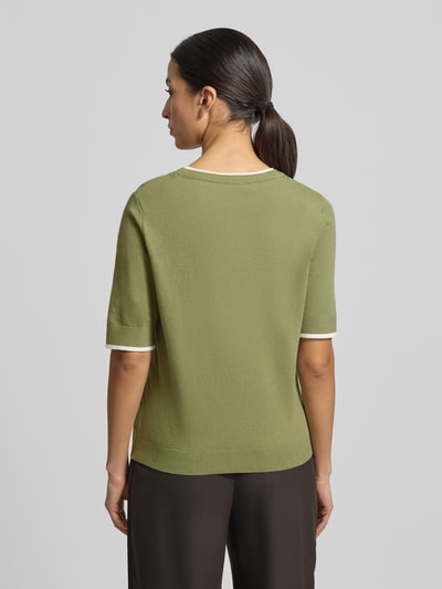 Modelka nosi Regular Fit Strickpullover mit Rundhalsausschnitt od More & More w zielonym kolorze, mieszanka wiskozy, elastyczne wykończenia, półrękaw, widok całej sylwetki z tyłu.