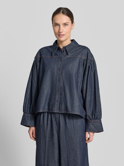 Modelka kobieca ma na sobie Relaxed Fit Jeansbluse Modell 'SELENI' od Drykorn, jeans w kolorze ciemnoniebieskim, bawełniana faktura, kołnierz koszulowy, zapięcie na guziki, Ganzkörperansicht von vorne, długość tyłu 64 cm, długość rękawa 57 cm w rozmiarze 36.