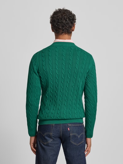 Męski model nosi Sweter z dzianiny z ściegiem warkoczowym i wyhaftowanym logo Gant, bawełna, krój slim fit, zielony, widok całej sylwetki z tyłu.