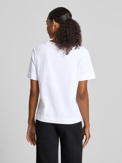 Modelka kobieca ma na sobie Regular Fit T-Shirt aus reiner Baumwolle von Rich & Royal, damski t-shirt z bawełny, krój regular fit, nadruk z motywem, obszycie z kamieni stras, długość tyłu w rozmiarze S: 57 cm, widok sylwetki od tyłu.