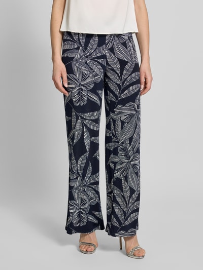 Kobiece modelka nosi Hose im Allover-Look mit Eingrifftaschen od Vera Mont, ciemna tkanina z białym wzorem liści, materiał z domieszką stretchu, szerokie nogawki, szerokość w rozmiarze 36: 39 cm, długość nogawki wewnętrznej 84 cm, widok całej sylwetki z przodu.